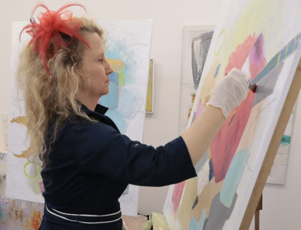 Das Foto zeigt die gegenständlich und figurative arbeitende Ölmalerin und Künstlerin  Diana Achtzig an ihrer Staffelei in ihrem Berliner Atelier.